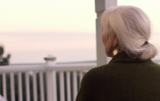 A senior women reflecting on Thanksgiving looking over the ocean on her terrace