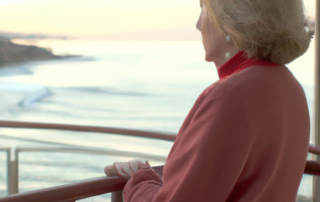 A senior women reflecting on Thanksgiving looking over the ocean on her terrace